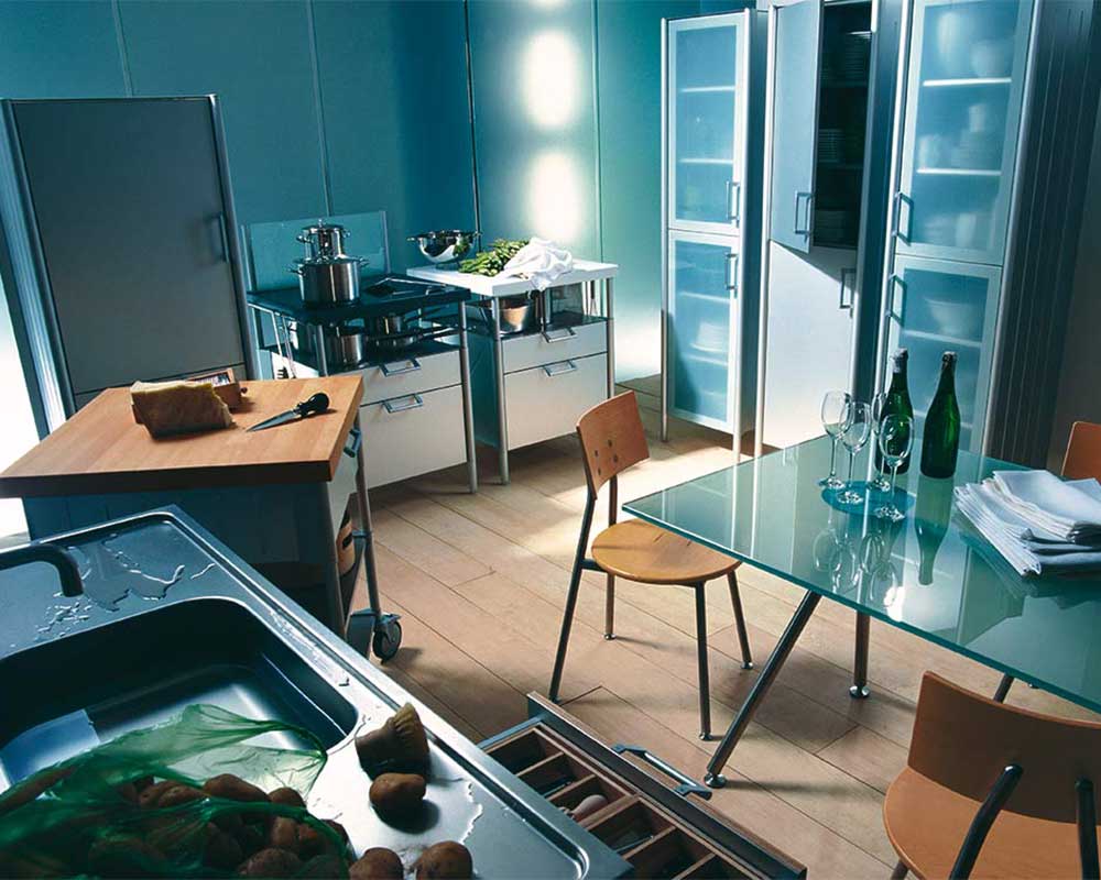 Modulare Küchenmöbel und ein Essplatz mit Glastisch stehen in einer kleinen Küche