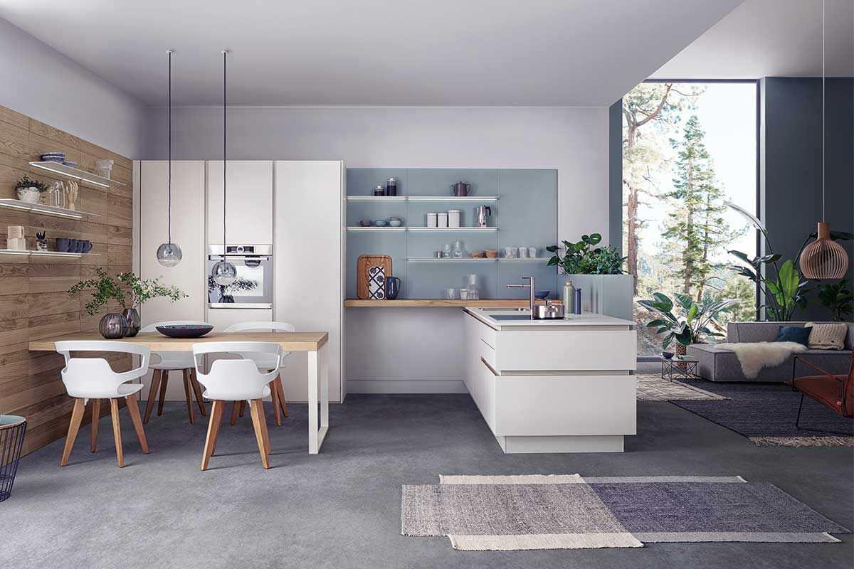 Moderne offene Wohnküche mit weißen Fronten, großer Kücheninsel und integrierten Essplatz.