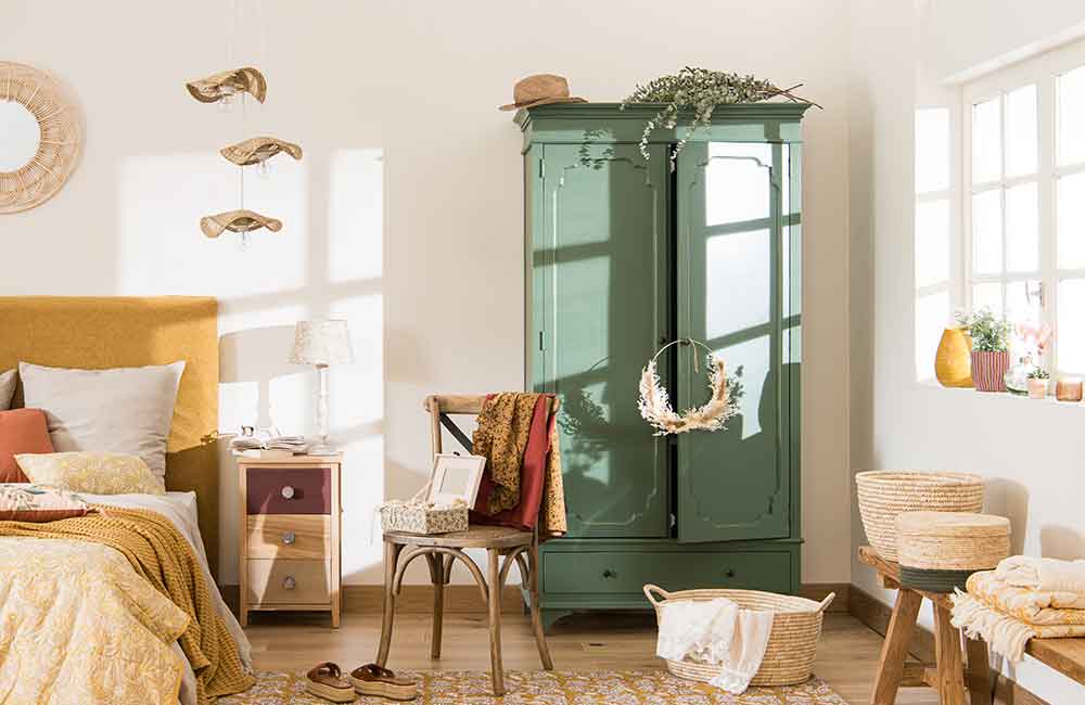 EEin grüner doppeltüriger Bauern-Kleiderschrank steht in einem proventialischen Schalfzimmer.