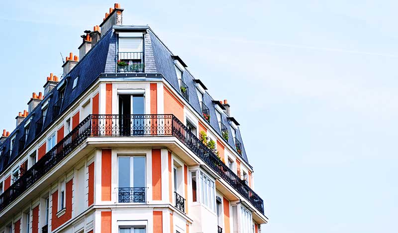 Farbenfrohes Eckhaus mit Mansadendach bodentifen Fenstern und Jugendstilbalkonen